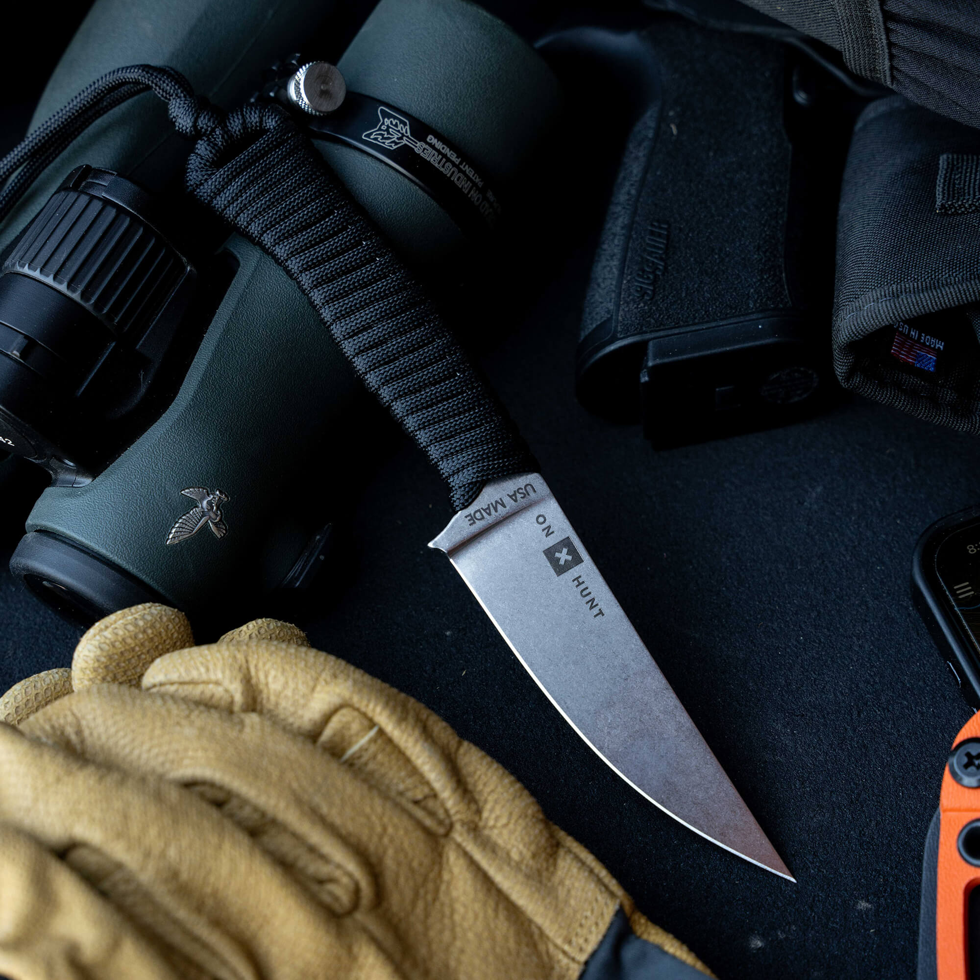 ONX Hunt Magnacut Speedgoat 2.0 knife displayed with gear, featuring a sleek blade and paracord handle, ideal for outdoor use.