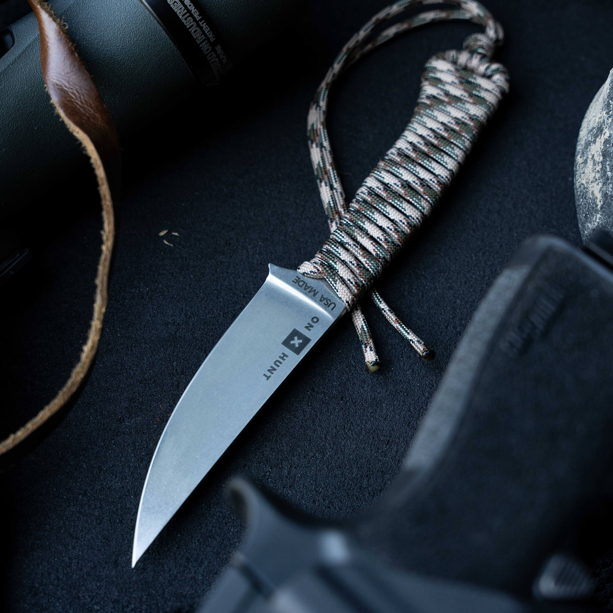 ONX Hunt Magnacut Speedgoat 2.0 knife with a textured handle and paracord lanyard, set against tactical gear.