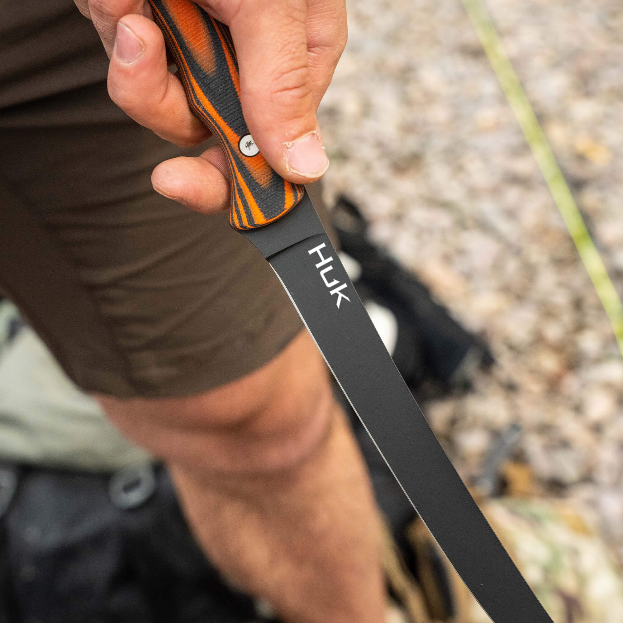 HUK Flathead Fillet knife held by a person, showcasing its sleek blade and textured handle, ideal for fishing and outdoor use.