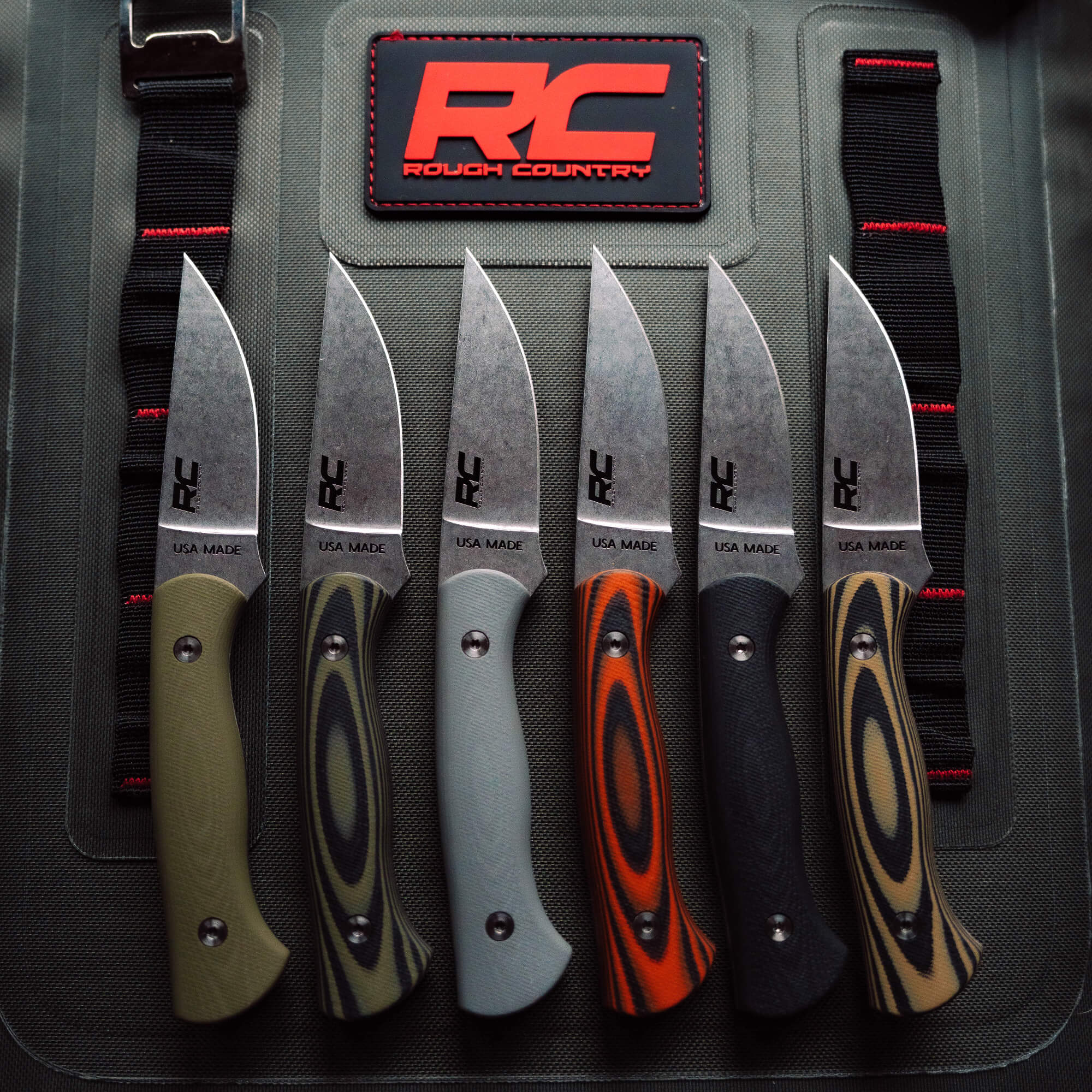 A collection of five Rough Country Blackfoot 2.0 knives featuring unique handle colors and textures, showcasing their American-made quality.