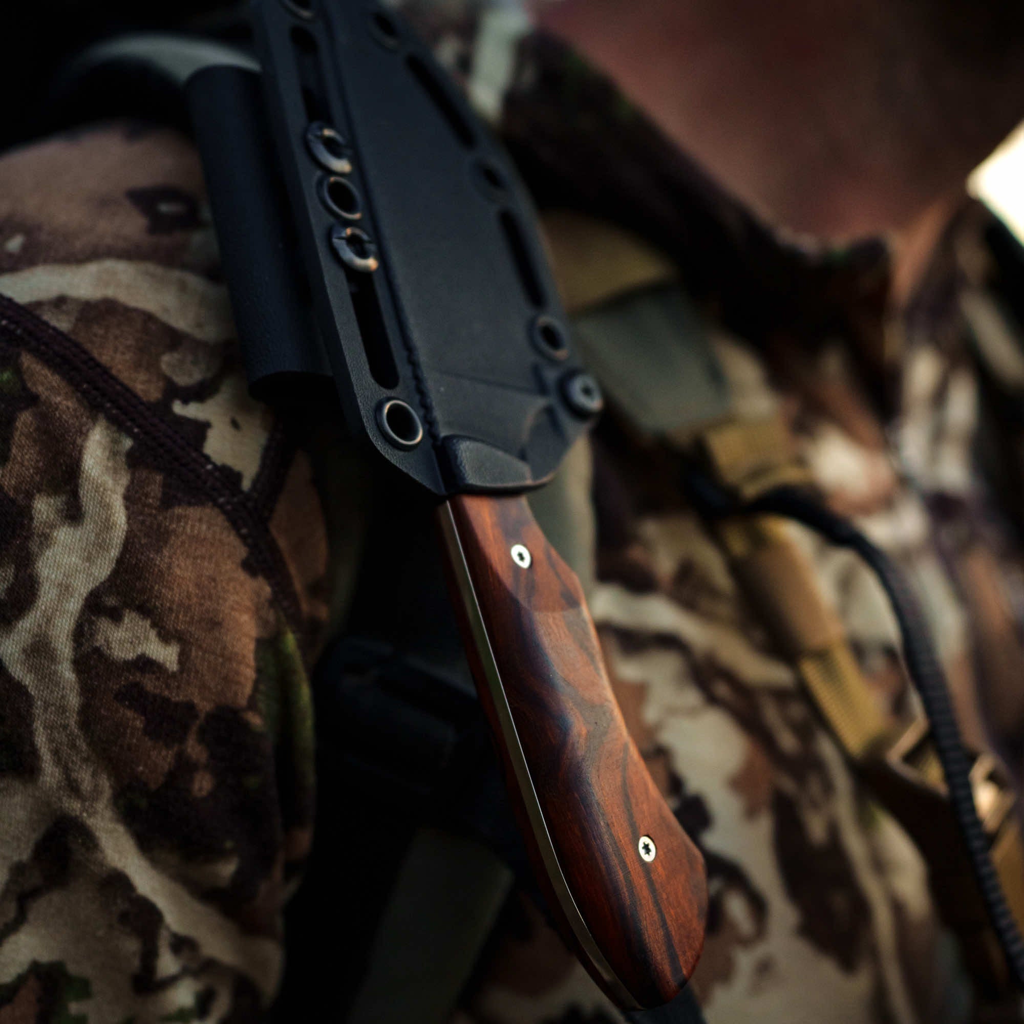 Montana Knife Company LIVE WILD Traditions Elk Knife secured in sheath on a camouflaged backpack.