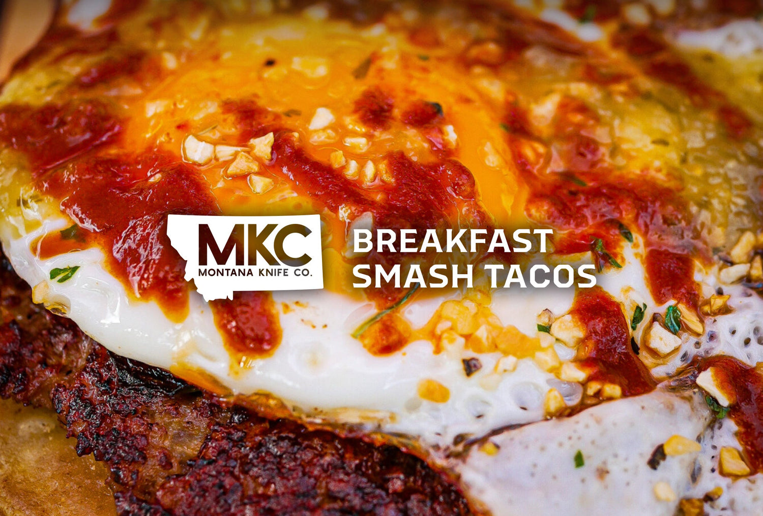 Close-up of a breakfast smash taco filled with sausage, eggs, bacon, and melted cheddar.