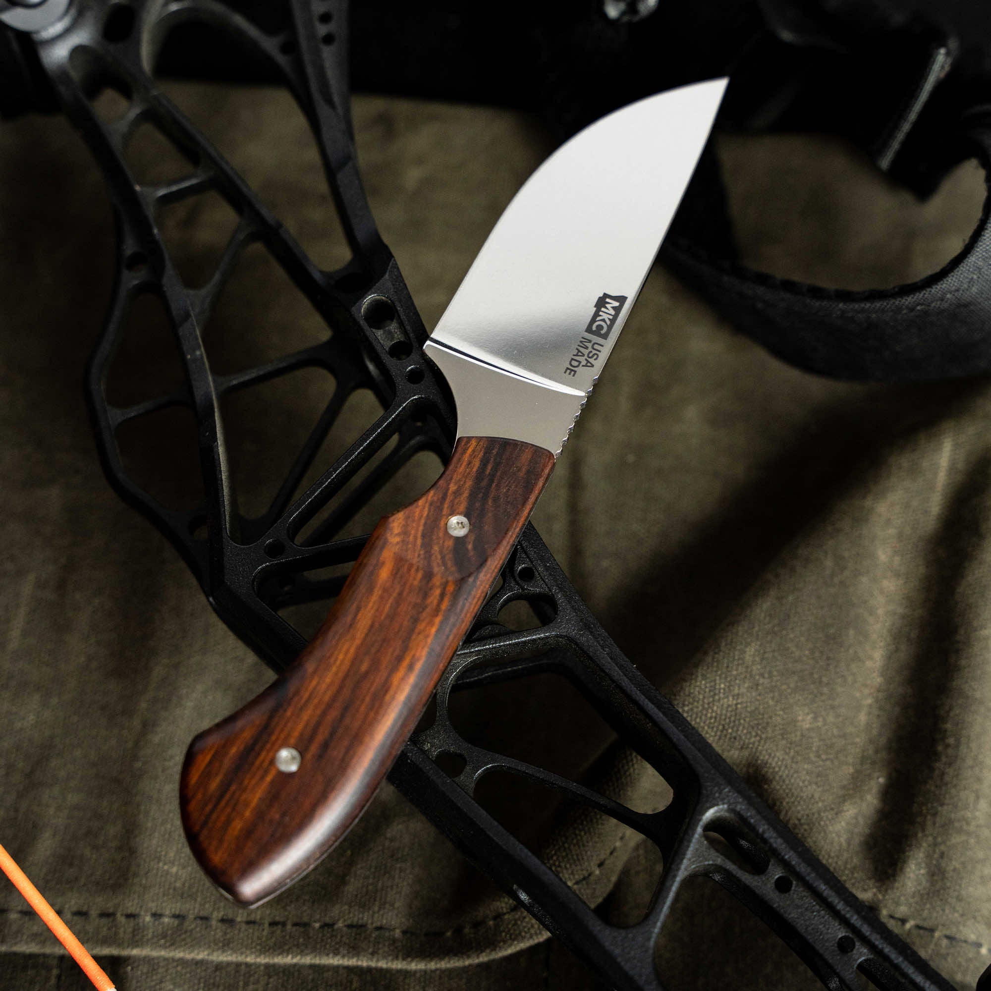 Montana Knife Company's LIVE WILD Traditions Elk Knife featuring a stainless steel blade and a wooden handle, placed on outdoor gear.