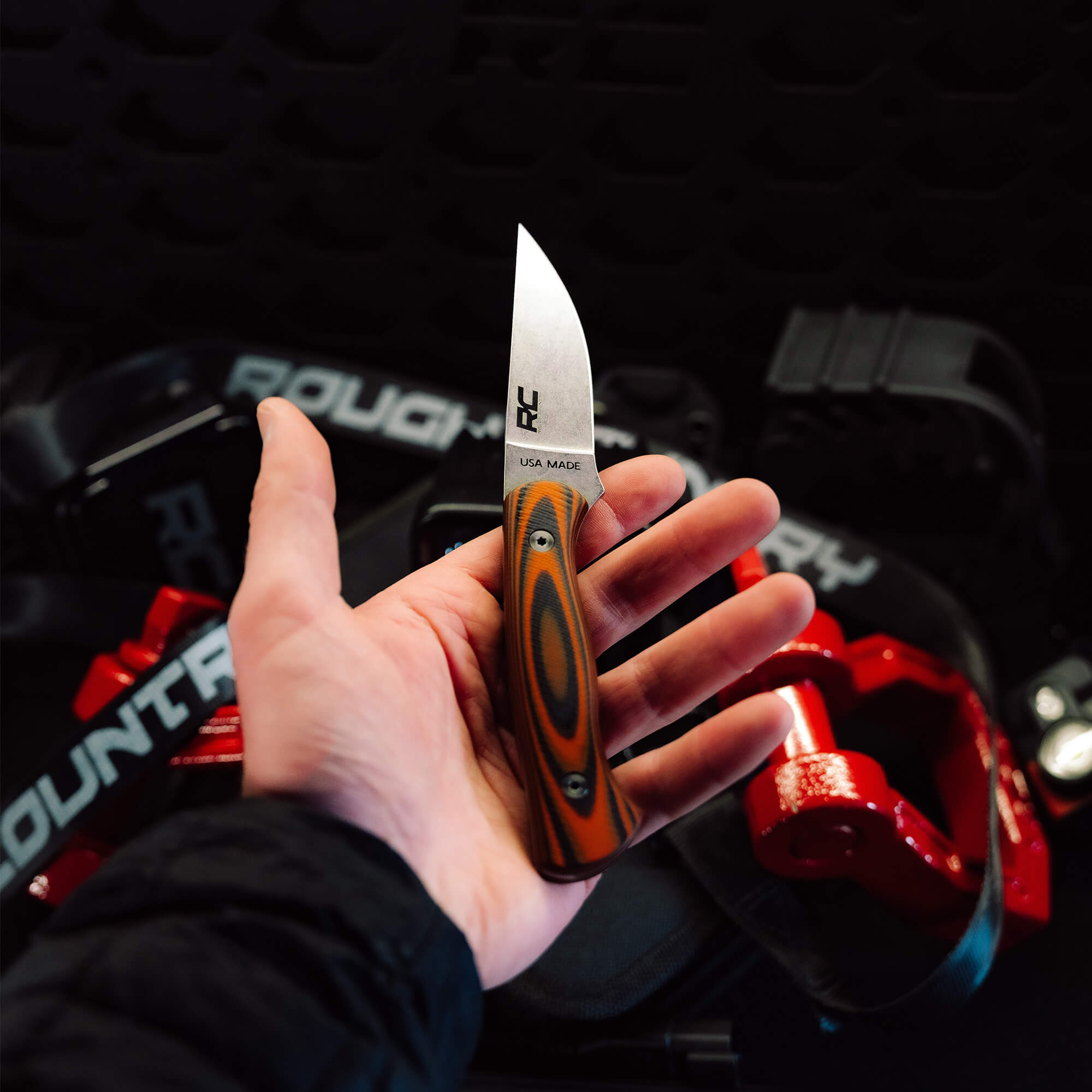 Hand holding the Rough Country Magnacut Blackfoot 2.0 knife, showcasing its sleek blade and striking handle design.