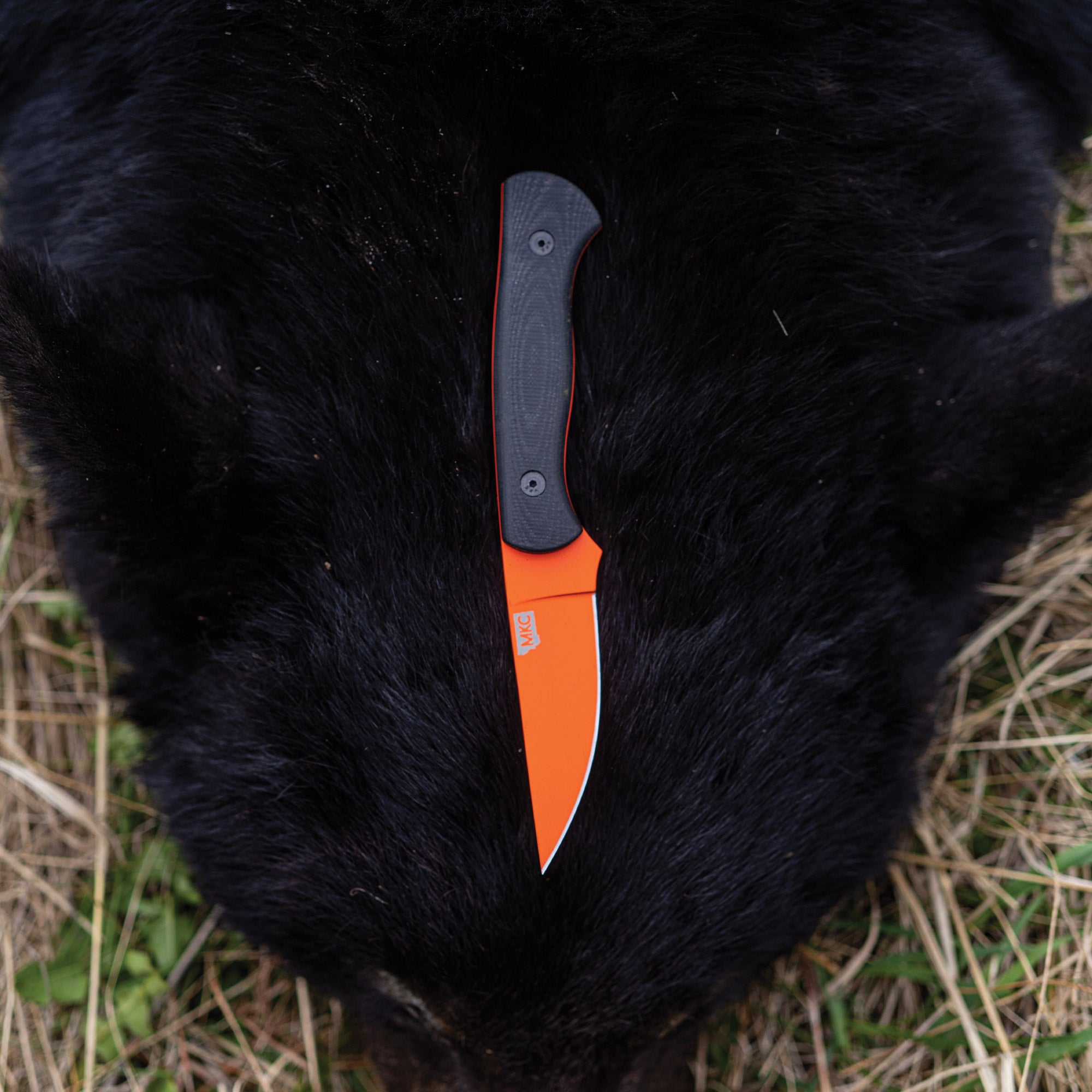 Orange and black BLACKFOOT 2.0 knife with a Blaze Orange Cerakote™ finish, displayed on a black fur background.