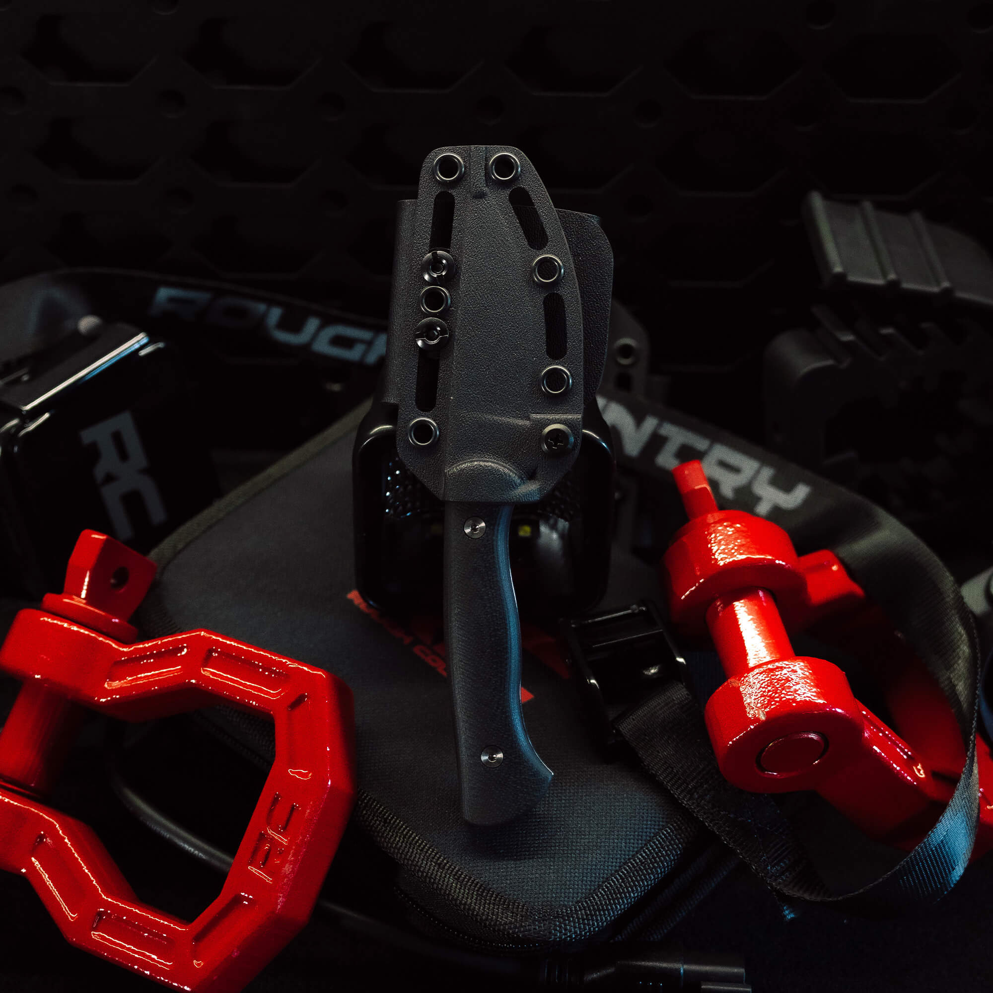 Rough Country Magnacut Blackfoot 2.0 knife with a gray handle and sheath, surrounded by red weightlifting equipment.