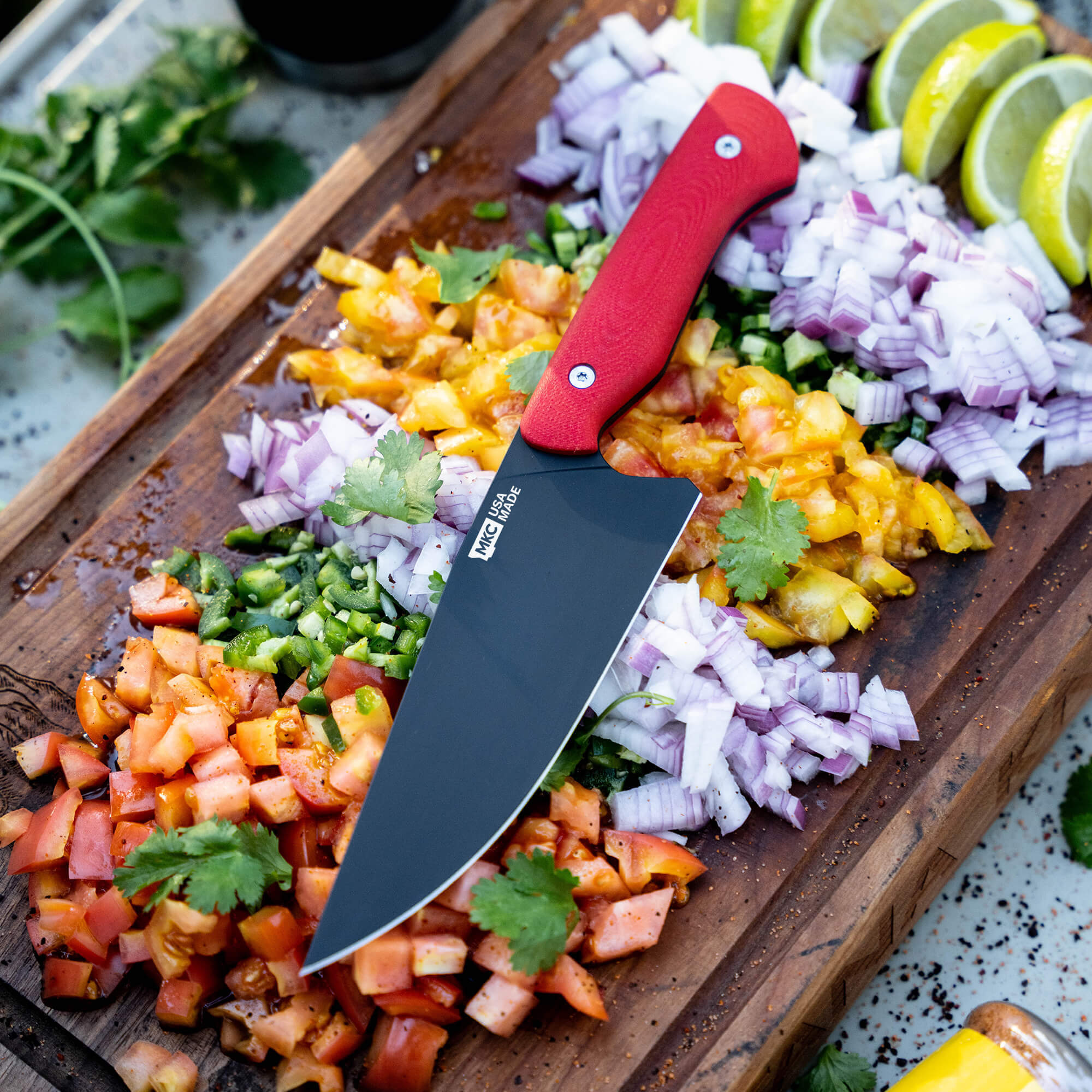 Red Meat Church chef knife on a wooden cutting board with chopped vegetables including tomatoes, onions, and limes.